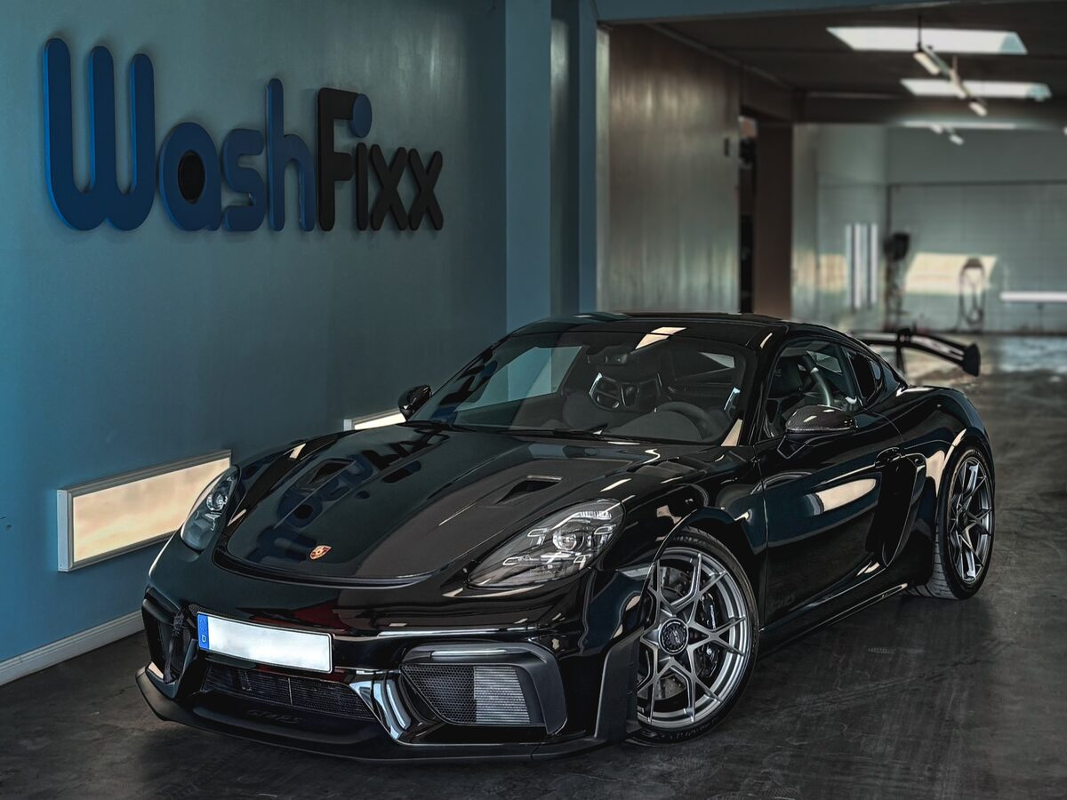 Schwarzer Porsche 718 GT4 RS vor dem WashFixx Schriftzug in der Halle in Lüneburg