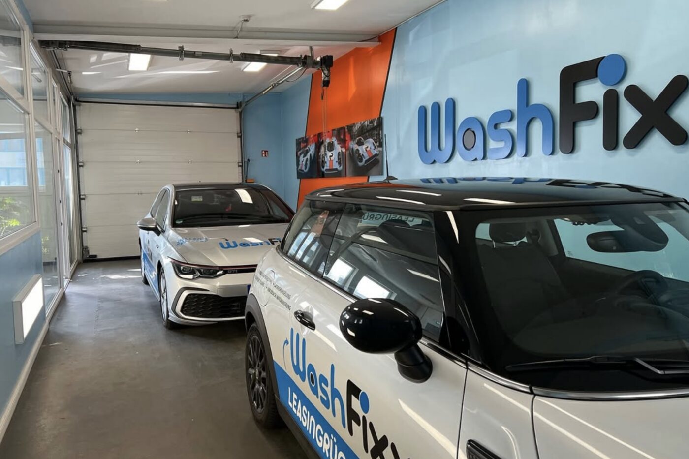 Die WashFixx Leihwagen, ein VW Golf und ein Mini im WashFixx-Design, in der Halle