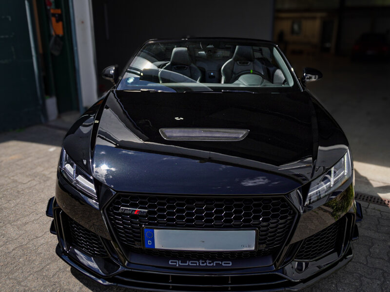 Glänzend schwarzer Audi TT RS von vorn vor der WashFixx Halle
